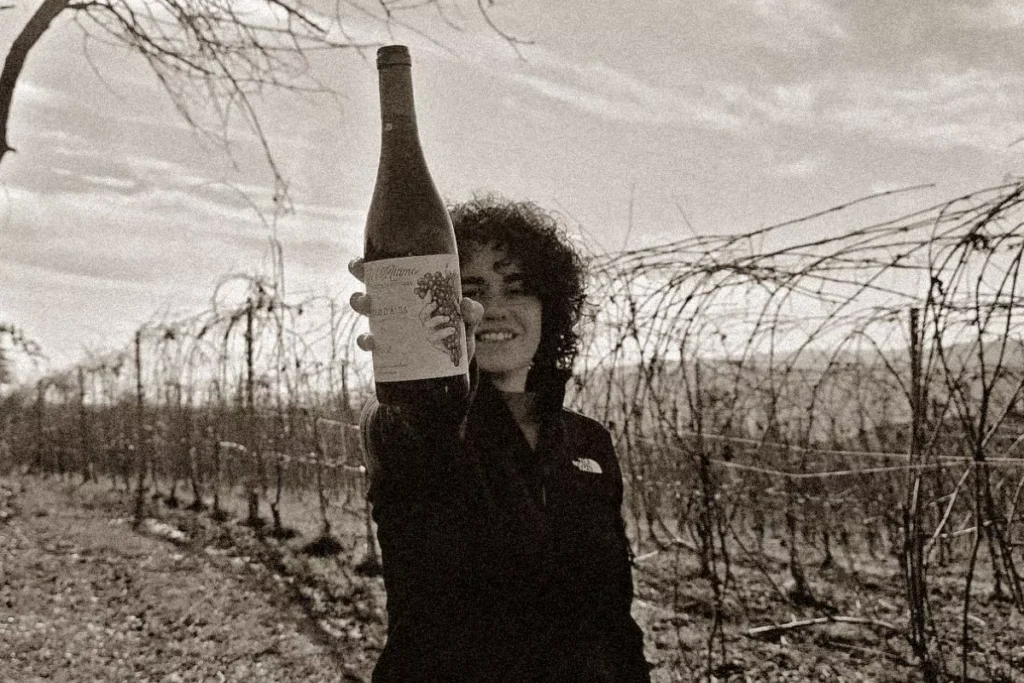 Serena Anselma mostra una bottiglia di Cogli l'Attimo tra i vigneti spogli di Novello nelle Langhe